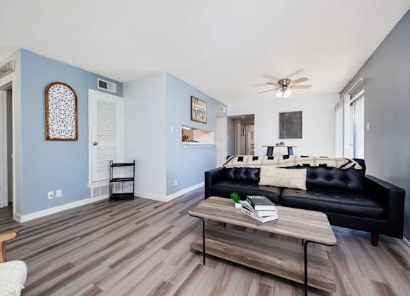 A living room with a black couch and a wooden coffee table.