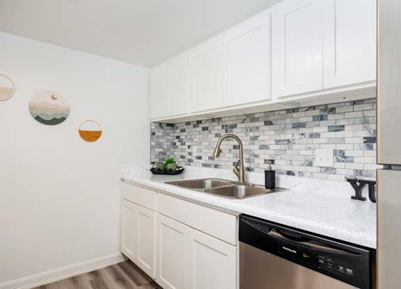 A kitchen with white cabinets and a black dishwasher.