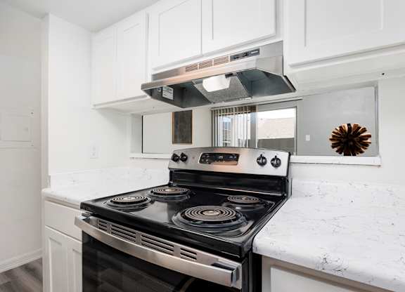 A modern kitchen with a stove top oven and white cabinets.