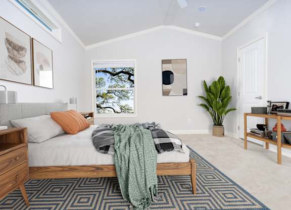 A bedroom with a bed, nightstand, and a window with a view of trees.