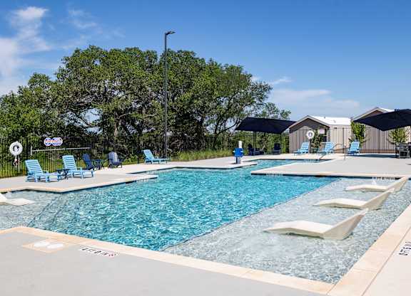 A large outdoor swimming pool with lounge chairs and umbrellas.