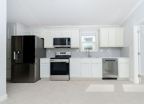 A kitchen with white cabinets and appliances.