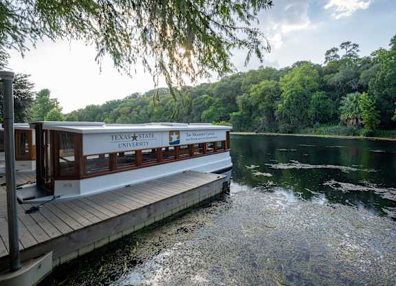 A Texas State University boat is docked at a pier.