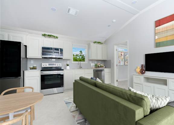 A modern kitchen with a green couch and wooden table.