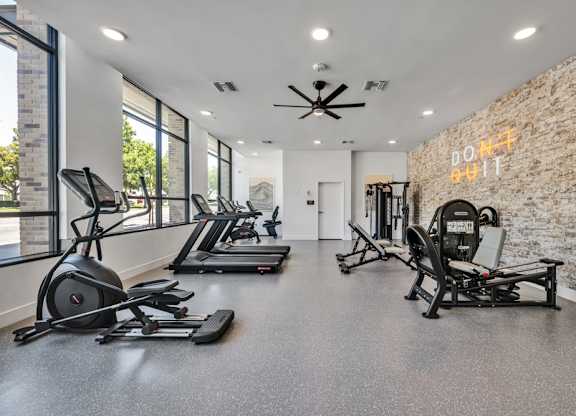 A gym with treadmills, elliptical machines, and a weight bench.