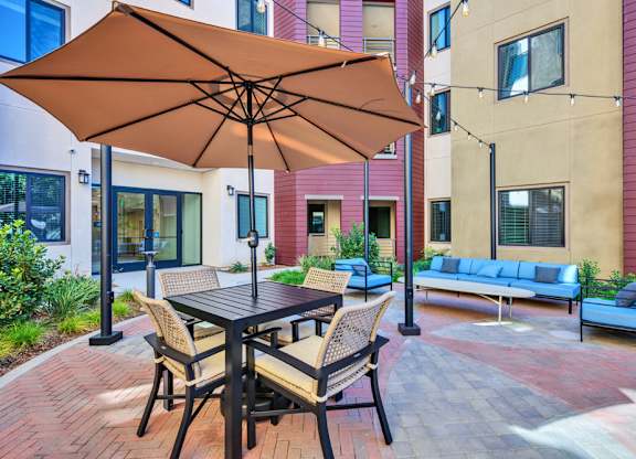 A patio with a table and chairs under an umbrella.