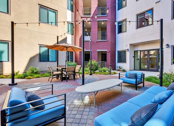 A patio with a blue couch and a table with chairs.