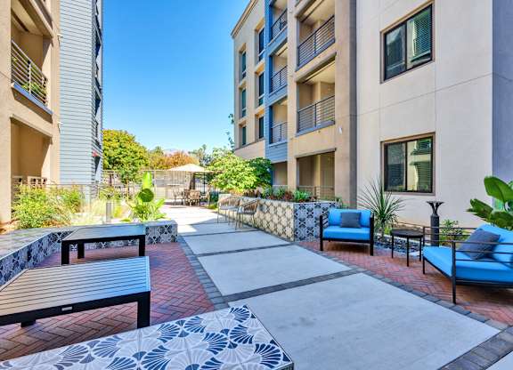 A patio area with blue couches and a brick floor.