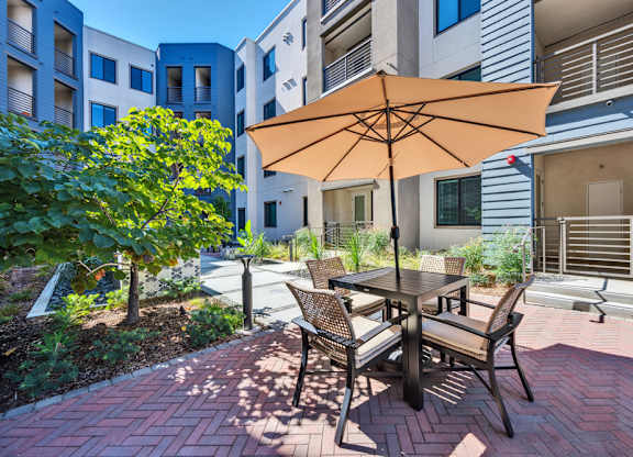 A patio with a table and chairs under an umbrella.