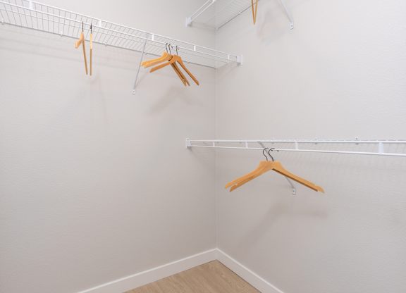 Three hangers are hanging on a white wall.