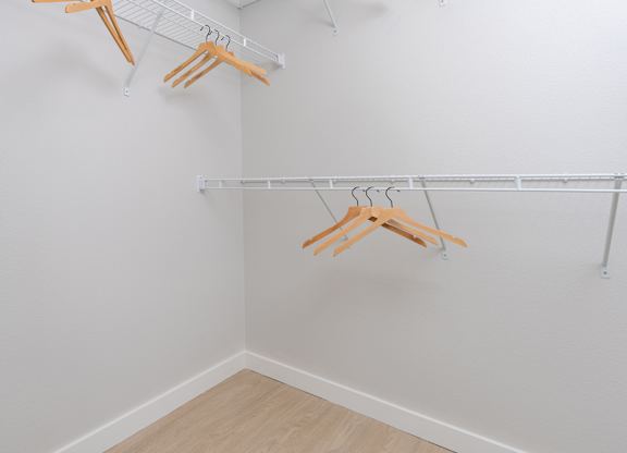 Three wooden hangers are hanging on a white wall.