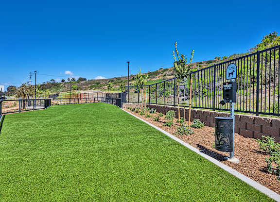 A green lawn with a fence and a sign on it.