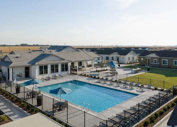 A swimming pool surrounded by a black fence and a grassy area.