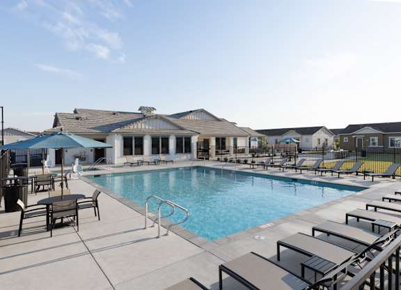 A pool area with sun loungers and a building in the background.