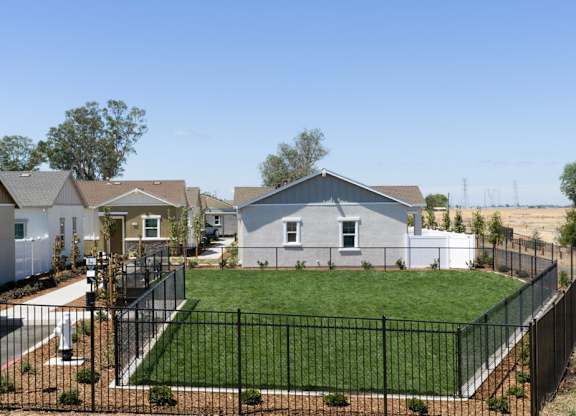 A house with a black fence and a green lawn.
