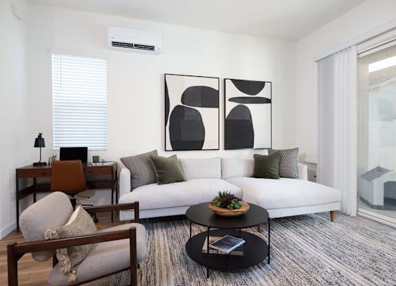 A modern living room with a white couch, a coffee table, and a large abstract painting on the wall.