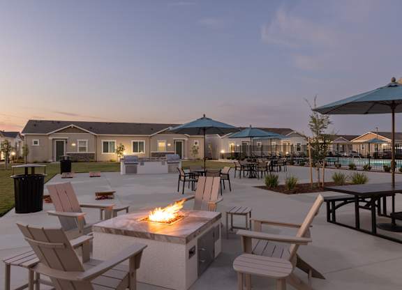 A fire pit is surrounded by chairs in a courtyard.
