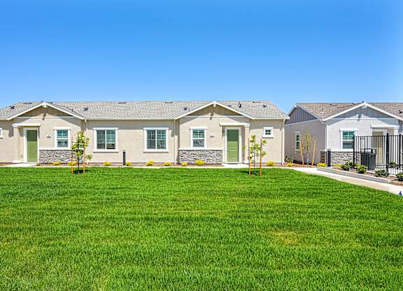 A row of houses with green lawns in front.