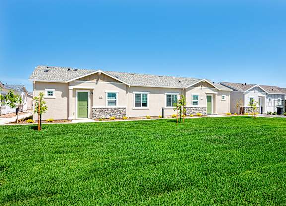 A row of houses with green lawns in front.