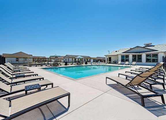A pool area with sun loungers and a clear blue sky.