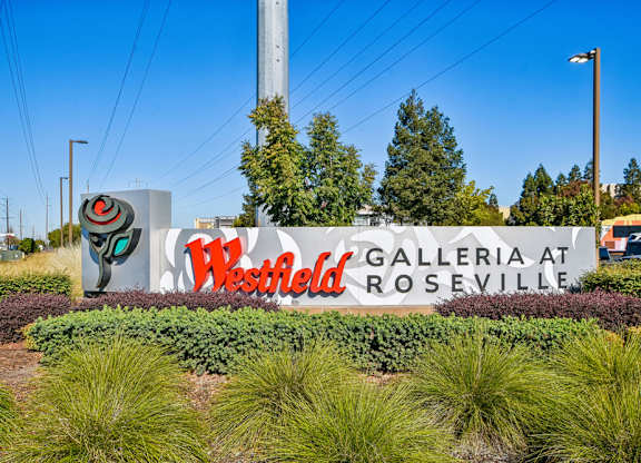 A sign for Westfield Galleria at Roseville is surrounded by plants.