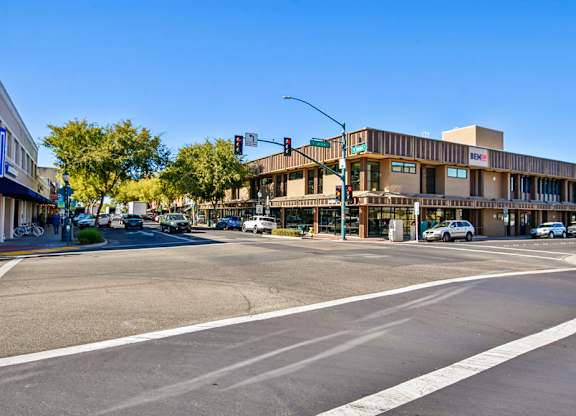 A street view with a building on the right and cars on the road.