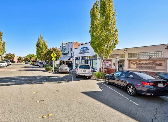 A street view with cars parked on the side and a few yellow objects on the road.