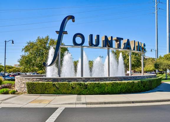 A large sign that says Fountains with water jets spraying out of it.