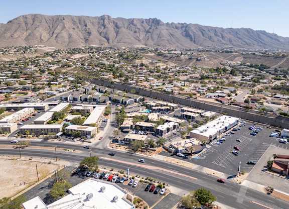 A parking lot is surrounded by buildings and a mountain in the background.