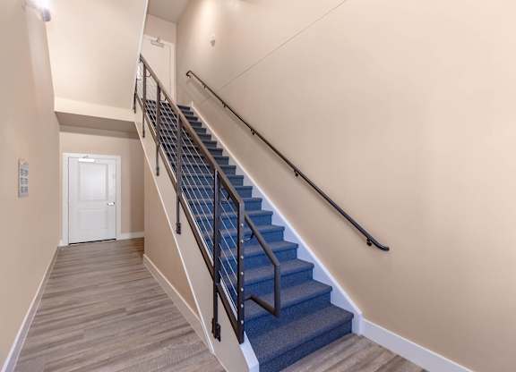 A staircase with a blue carpeted runner and wooden steps.