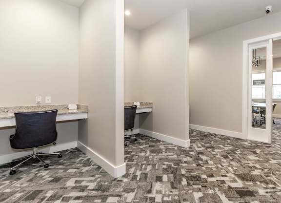A room with a carpeted floor and a desk with a chair.