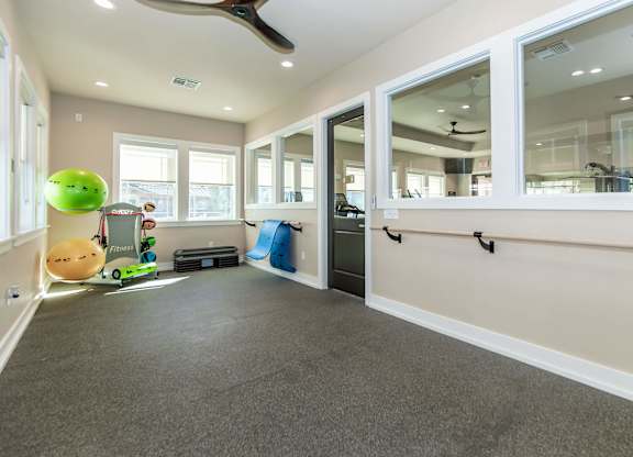 A room with a grey carpet and a ceiling fan.