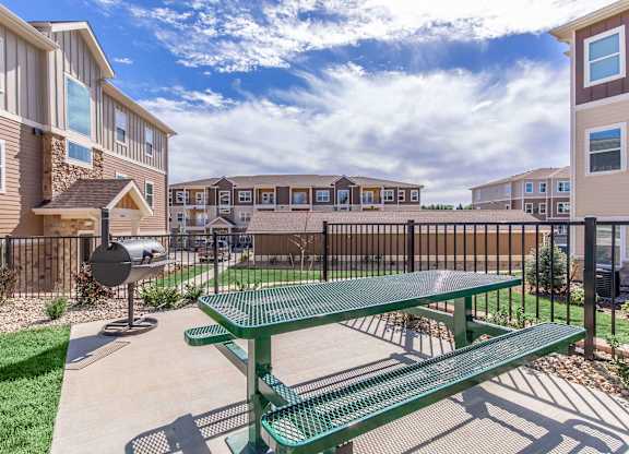 A green picnic table is in the foreground of a residential area.