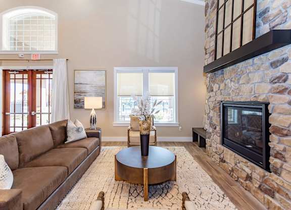 A living room with a brown couch and a stone fireplace.