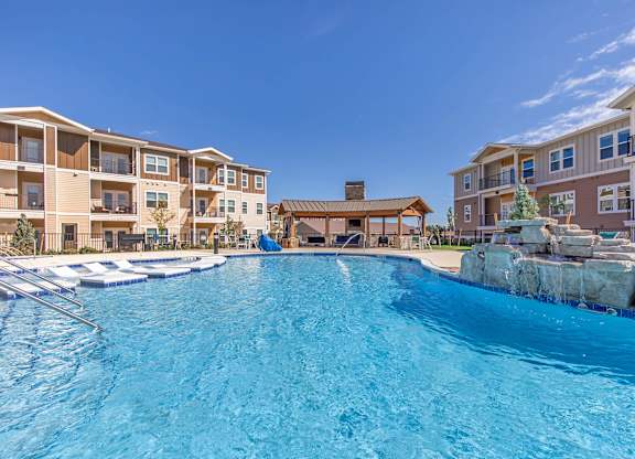 A large swimming pool in front of a resort.