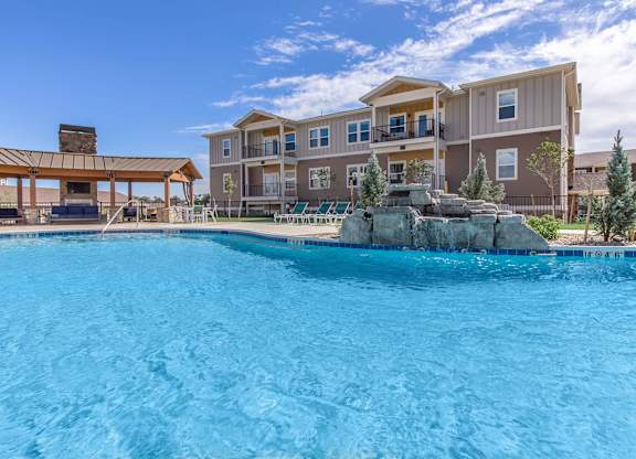 A large swimming pool in front of a multi-story apartment building.