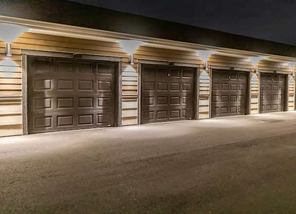 A row of garage doors are illuminated by overhead lights.