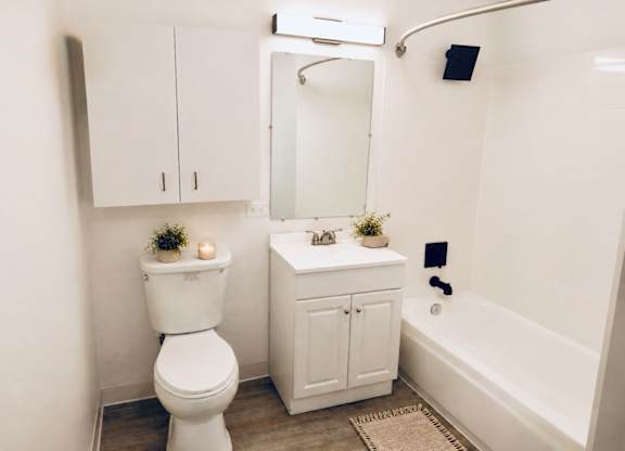 A white toilet sits next to a white sink in a small bathroom.