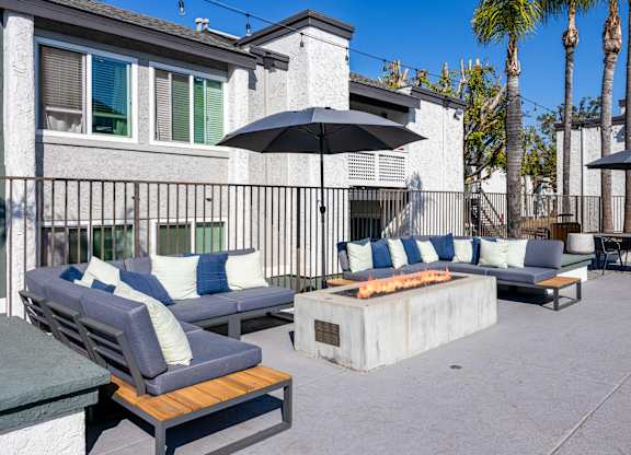 A patio with a black umbrella and blue cushions at Verandas Apartments, West Covina, California