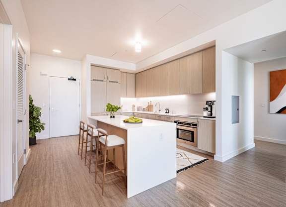 A modern kitchen with wooden floors and a white island.