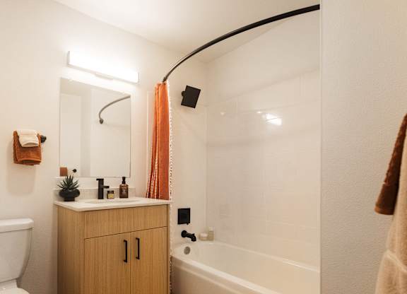 A bathroom with a white tub and a wooden cabinet.