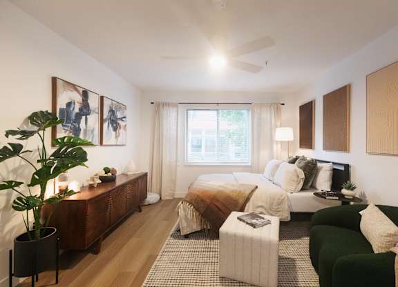 A bedroom with a bed, a couch, and a potted plant.