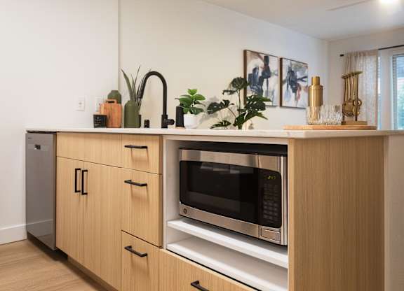 A modern kitchen with wooden cabinets and a microwave oven.