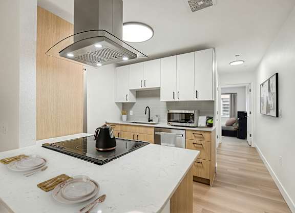 A modern kitchen with a white countertop and wooden cabinets.