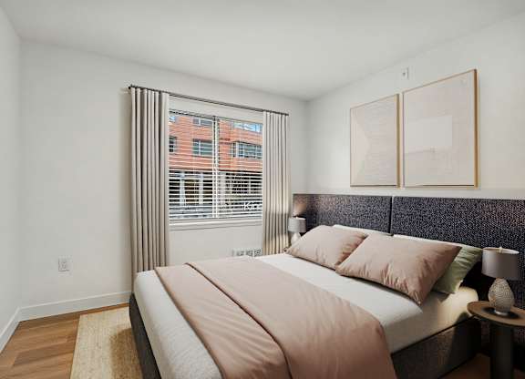 A bedroom with a large bed and a window with blinds.