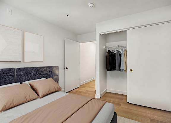 A bedroom with a bed, pillows, and a closet.