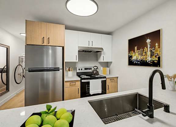 A kitchen with a refrigerator, sink, and a painting of a cityscape on the wall.