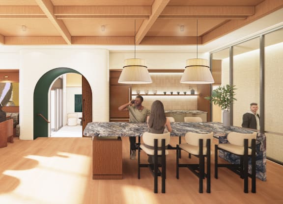 A group of people are sitting around a table in a room with a green archway.