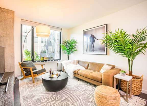 A living room with a brown couch, a coffee table, and a large window.at The Rise, San Francisco California  