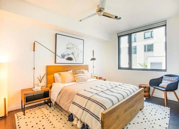 A bedroom with a bed, a chair, and a painting on the wall.at The Rise, San Francisco, CA  
